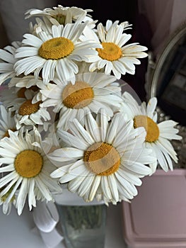 The girl holds a bouquet of wild flowers in her outstretched hand.  Big daisies.  Shot from above against the background of paving