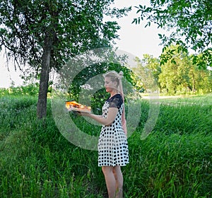 Girl holds a burning book in her hands. A young woman in a forest burns a book