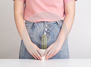 The girl holds a cactus against the background of the pubic zone of the urological and reproductive system. Concept of