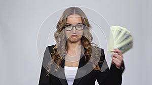 Girl holds cash dollar banknotes and takes credit card choosing between them nods approvingly at card