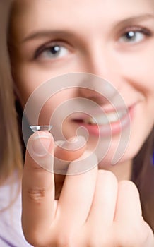 A girl holds a contact lens