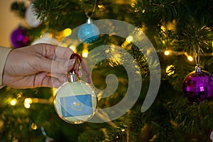 a girl holds a decoration on a Christmas tree with the flag of Kazakstan