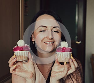 The girl holds delicious cupcakes with white cream in her hands, decorated balls with coconut powder