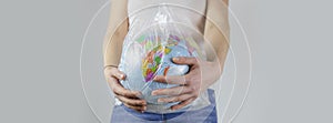 Girl holds an earth globe in a plastic bag. plastic free concept, eco friendly, zero waste lifestyle, conscious resource