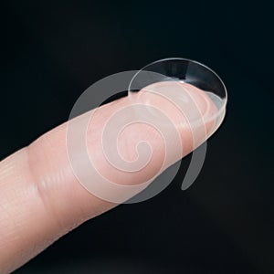 Girl holds finger on a contact lens, closeup