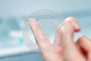 Girl holds finger on a contact lens, closeup