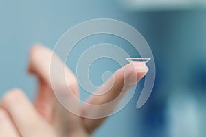 Girl holds finger on a contact lens, closeup