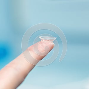 Girl holds finger on a contact lens, closeup