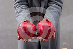 The girl holds a fresh ripe ruby â€‹â€‹pomegranate in her palms