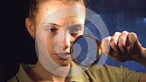 A girl holds in front of a magnifying glass and looks at your face