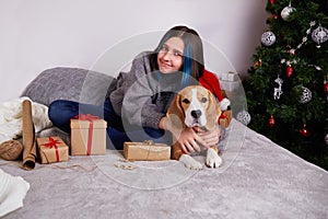 A girl holds a gift box in her hands and hugs beagle dog.