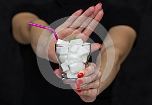 Girl holds a glass filled with cubes of white sugar, rejects the use of sugar photo