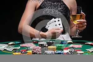 Girl holds a glass of wine. Poker player shows a winning combination in cards against the background of chips, money. Concept of a