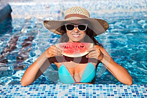 A girl holds half a red watermelon over a blue pool, relaxing o