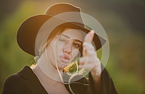 Girl holds hands like a gun. Portrait of young woman simulate shooting with and fingers outdoor. Romantic western girl