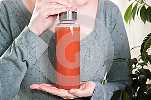 Girl holds in hands water bottle with fresh juice, Mock-up, trendy photo