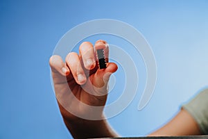 A girl holds in her hand and examines a small black chip