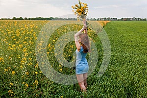 The girl holds in her hands a bouquet of rapeseed and spikelets of wheat