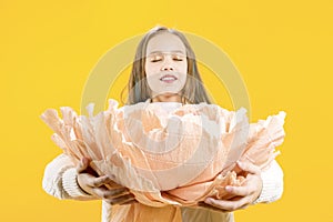 The girl holds in her hands a huge peony flower on a yellow background, inhales the aroma. Beautiful bud.