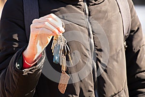 The girl holds in her hands the keys to the apartment on the street in the sun, the keys to the house, buying