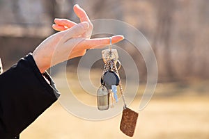 The girl holds in her hands the keys to the apartment on the street in the sun, the keys to the house, buying