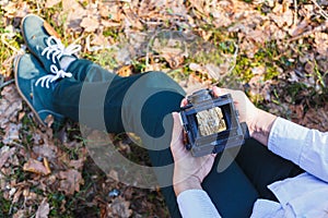 A girl holds in her hands an old film photo camera in the spring forest