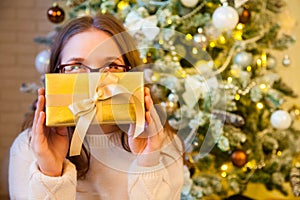 The girl holds in her hands and opens a Christmas golden gift. L