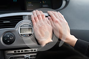 The girl holds her hands over the car& x27;s hot air outlet. Cold hands.
