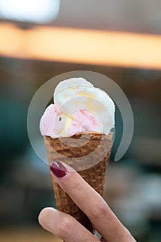 A girl holds ice cream cones with strawberry and vanilla