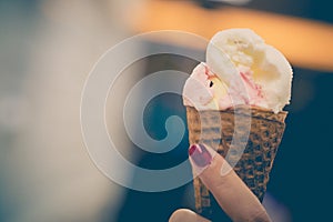 A girl holds ice cream cones with strawberry and vanilla