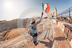 Girl holds Italian flag standing on the steps of an ancient Roman amphitheater. The concept of uniting Italy in the face of a