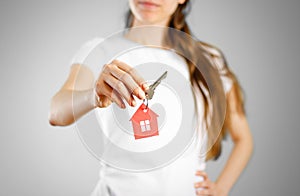 A girl holds the keys to the house. Key ring red house