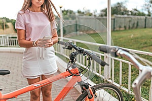 Girl holds mobile phone hand, photographs parking bicycle. In summer city application online, Internet post in social