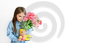 Girl holds multicolored painted Easter eggs and a bouquet of pink tulips