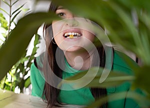 The girl holds a pill or capsule in her mouth. Young woman holding a tablet with her teeth close-up. Medical concept and treatment