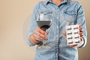 A girl holds a pill with a glass of wine, a ban on drugs for alcohol, the choice of treatment or alcohol