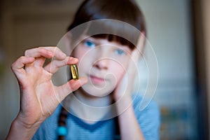 Girl holds a pill in her hand, headache and cold