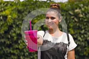 The girl holds a pink glass with water