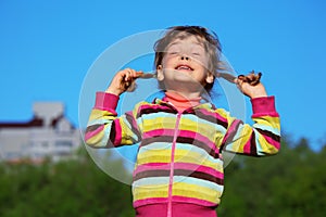 Girl holds plaits and has closed eyes