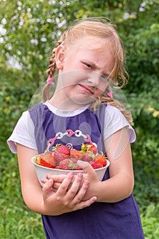 The girl holds a ripe juicy red fragrant strawberry in her hands.