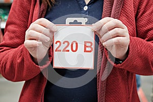 Girl holds sign with russian letter. Label warns of electrical of 220 volts