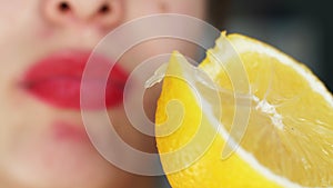 Girl holds slice of lemon in her hands and licks her lips.