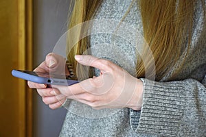 Girl holds smartphone in her hands. She browses website information on mobile phone screen