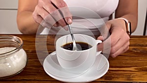 Girl holds a spoon and strews sugar to mug