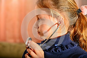 A girl holds a stethoscope in his hands and listens to the patient, home game at the doctor