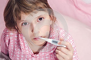 The girl holds a thermometer in a mouth