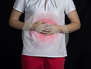 The girl holds on to the stomach on a black background, stomach pain, gastritis and ulcer