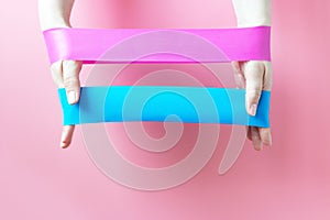The girl holds two fitness gums, Espander, on pink background, view from above
