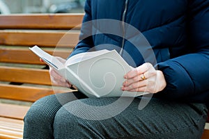 A girl holds a white book in her hands.