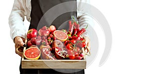 Girl holds wooden tray with fresh red vegetables and fruits on white background. Healthy eating vegetarian concept.